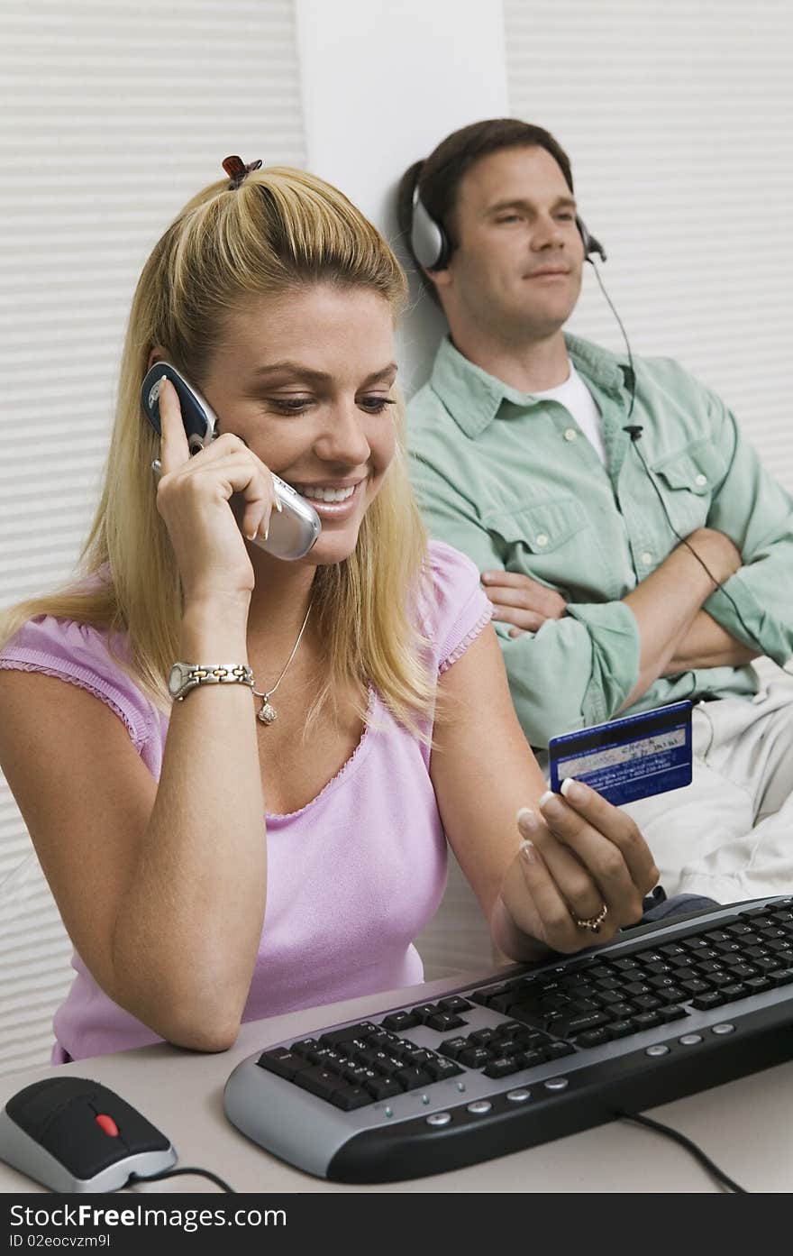 Woman Using Computer While Husband listens to music. Woman Using Computer While Husband listens to music