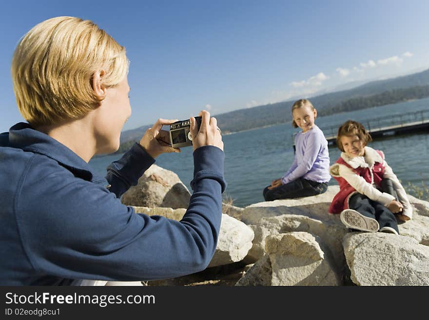 Mother taking picture of daughters at the lake