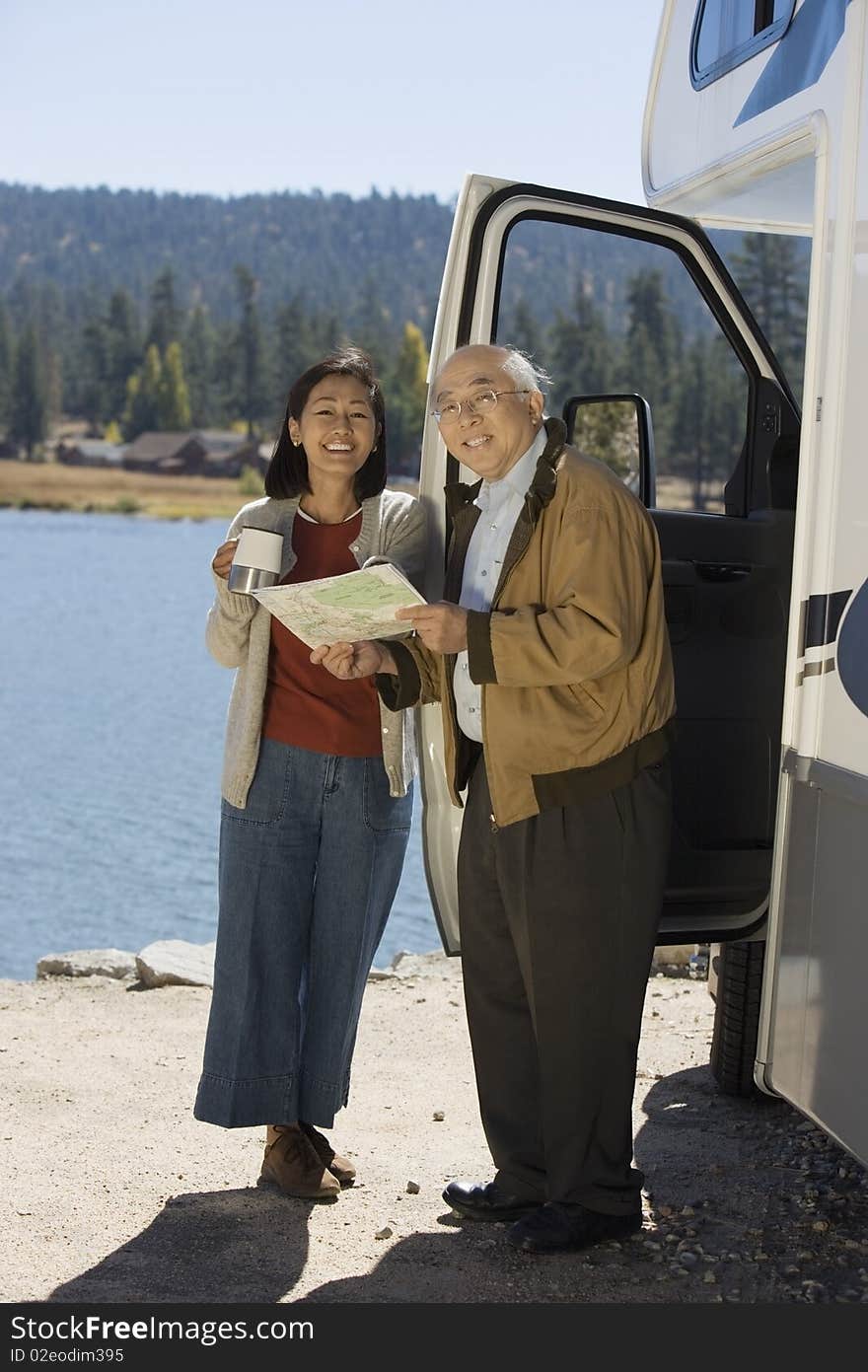 Senior couple looking at map outside RV at lake