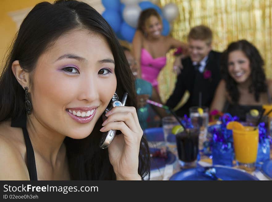 Well-dressed teenager girl using cell phone at school dance