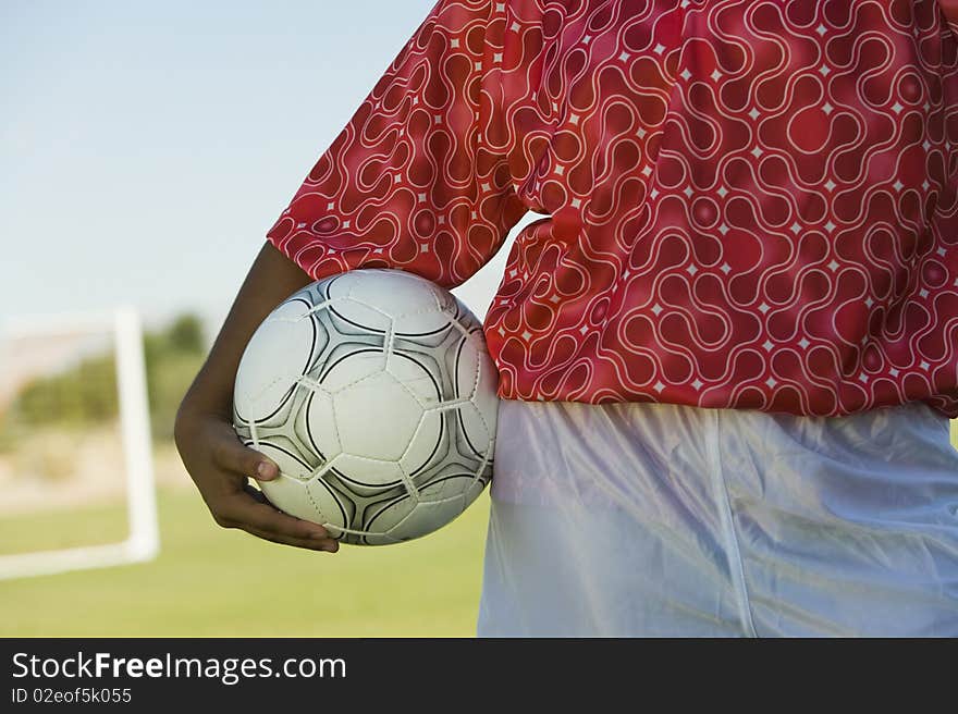 Girl (13-17) holding soccer ball, mid section