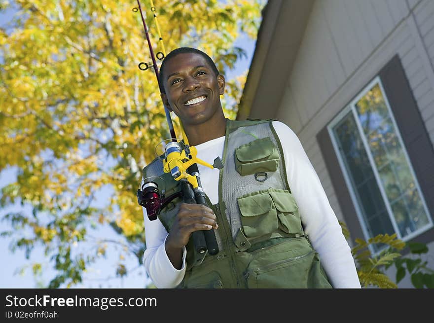 Man holding fishing rod in front of house