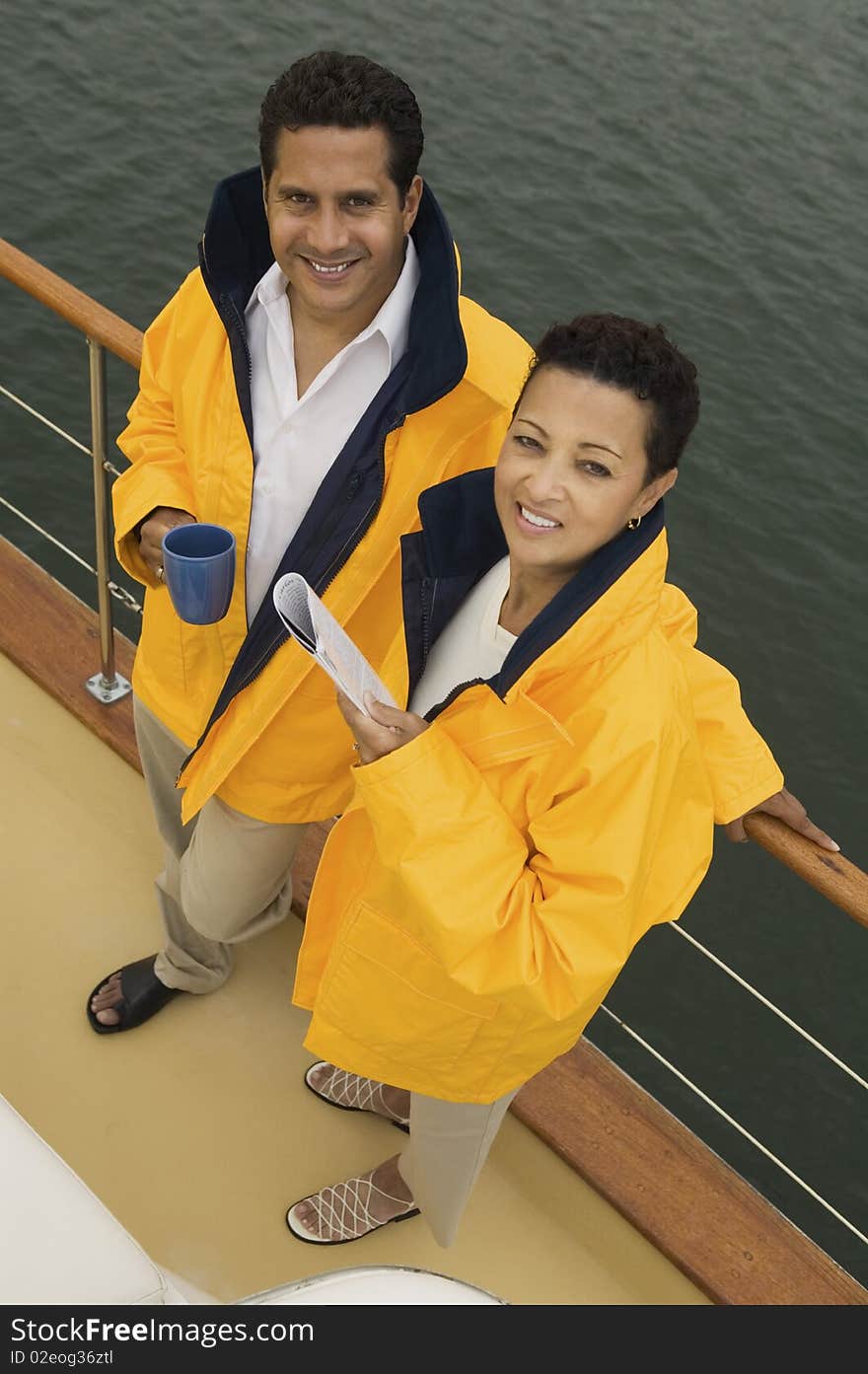 Couple wearing yellow anoraks on yacht