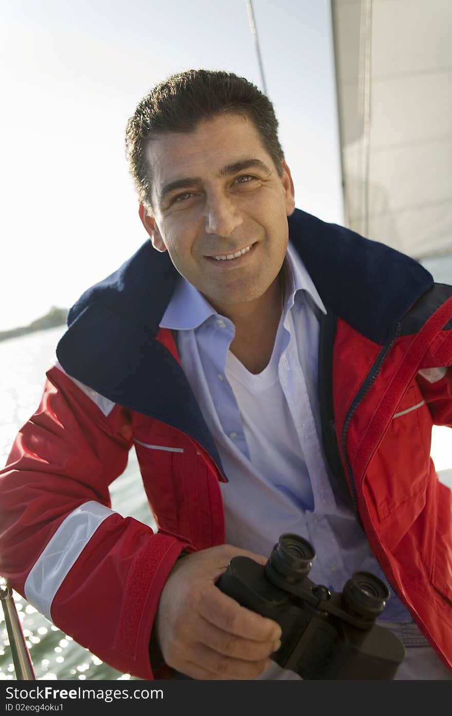 Man holding binoculars on yacht, (portrait)