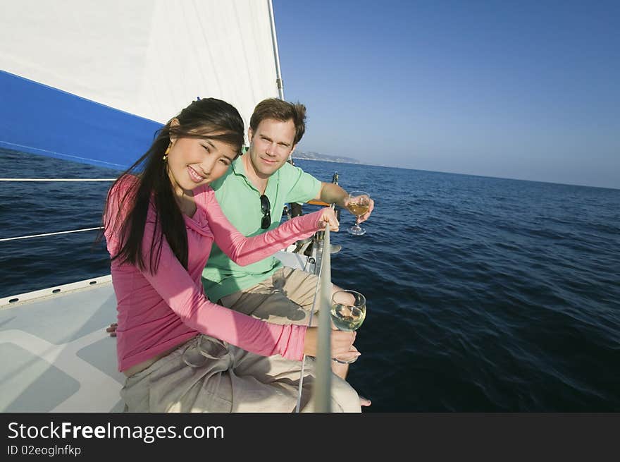 Couple dinking white wine on sailboat, (portrait)