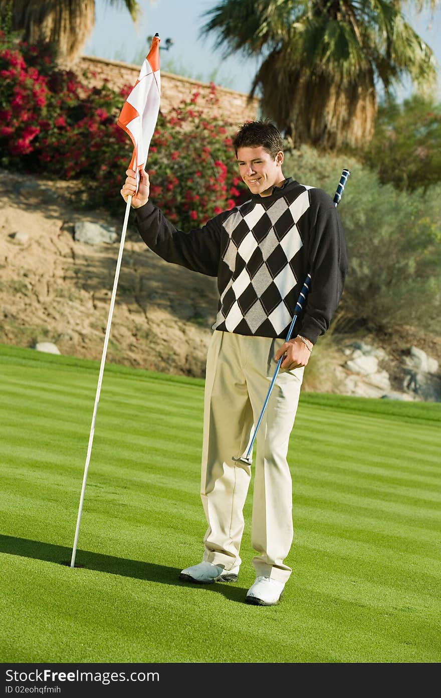 Golfer holding flag and club