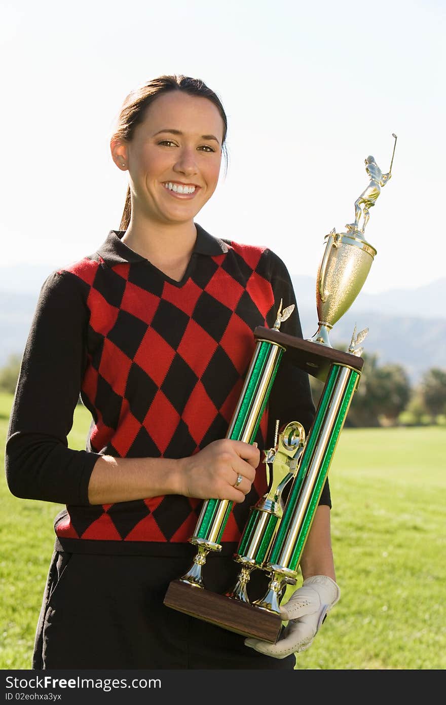 Female golfer holding trophy, (portrait)