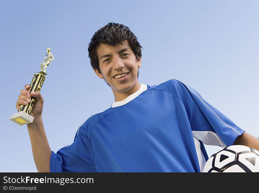 Soccer player holding trophy and ball