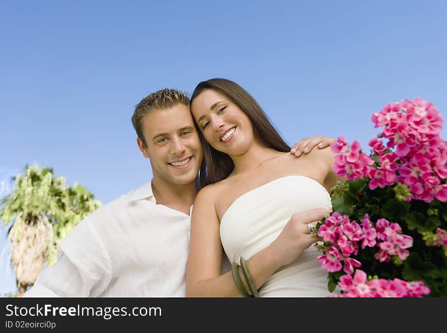 Young couple with potted flower against clear sky, (portrait), (low angle view)