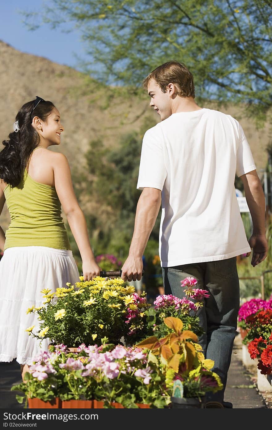 Young couple pulling cart with potted flowers