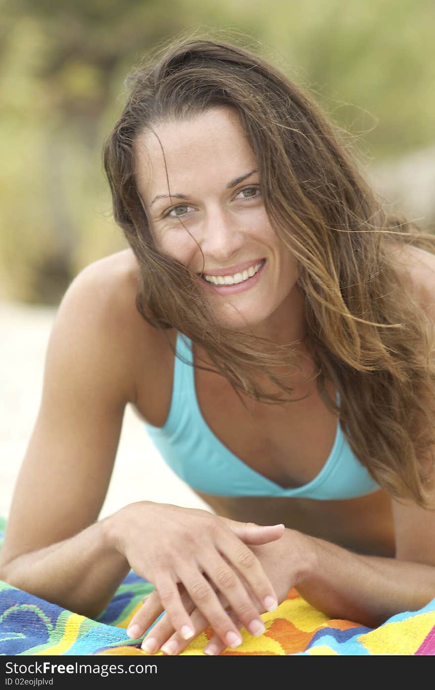 Smiling Young Woman Lying Down On Beach Towel