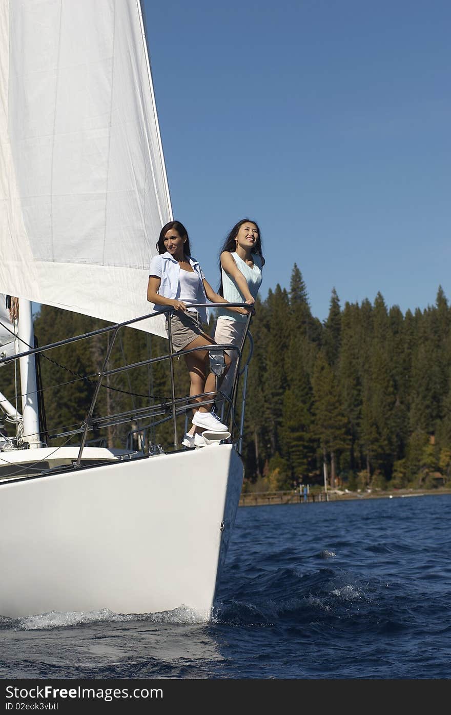 Two young women standing on sailboat