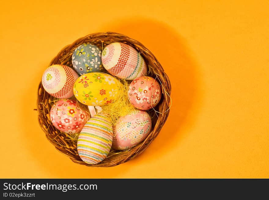 Decorated easter eggs in a basket and orange background