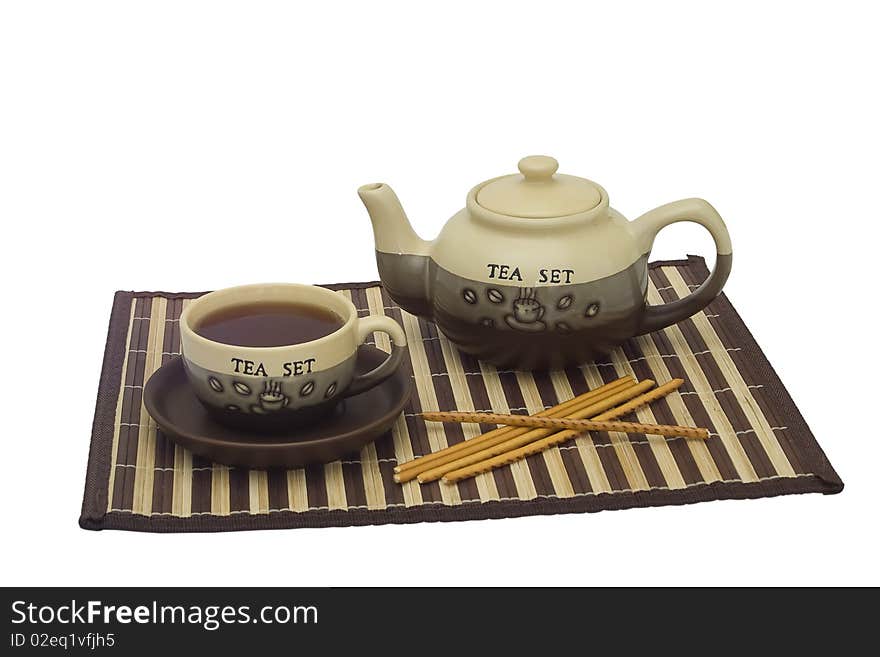 Ceramic cup and teapot on a napkin from a bamboo. Ceramic cup and teapot on a napkin from a bamboo