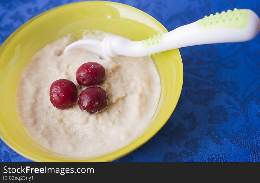 Children's food porridge in a yellow plate on a dark blue cloth. Children's food porridge in a yellow plate on a dark blue cloth