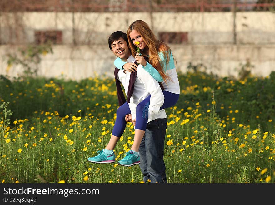 Young couple piggy-backing in meadow