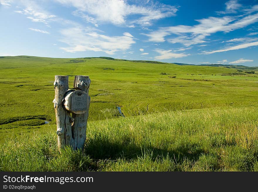 Weathered log mailbox with open grassy field and distant hills in BG. Sunny blue sky high white clouds. Name on mailbox is Bar S Ranch, Chataway. Weathered log mailbox with open grassy field and distant hills in BG. Sunny blue sky high white clouds. Name on mailbox is Bar S Ranch, Chataway.