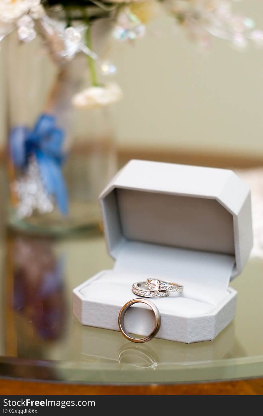 Wedding rings still life with floral bouquet in a vase in the background. Wedding rings still life with floral bouquet in a vase in the background.