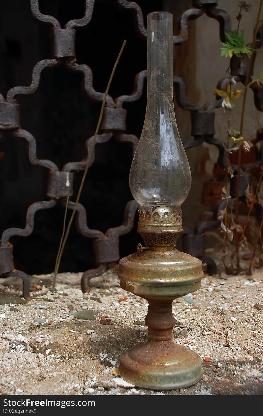 Shabby corroded Betty lamp in the background of the church grilled window. Shabby corroded Betty lamp in the background of the church grilled window.