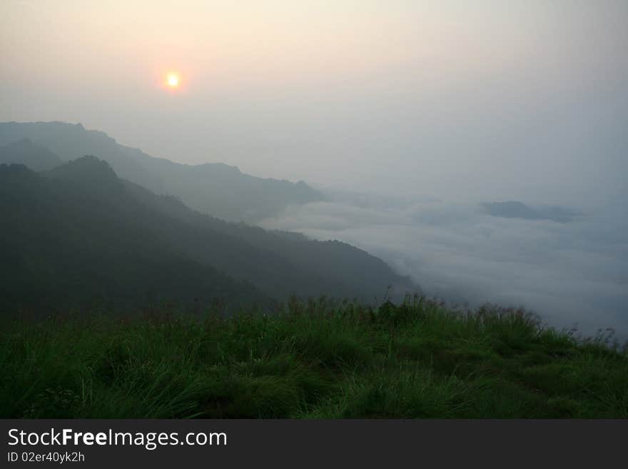 Sunrise beyond mountain with fog