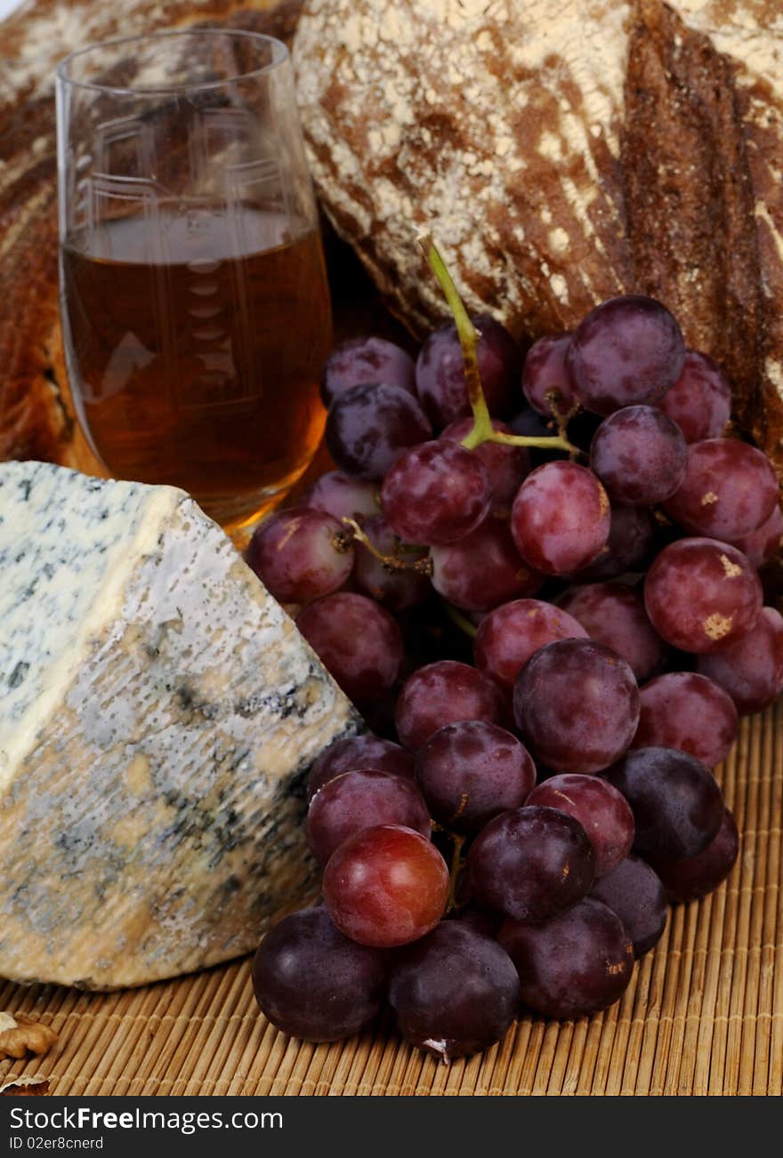 Close up with moldy cheese, glass, bread and red grapes isolated. Close up with moldy cheese, glass, bread and red grapes isolated