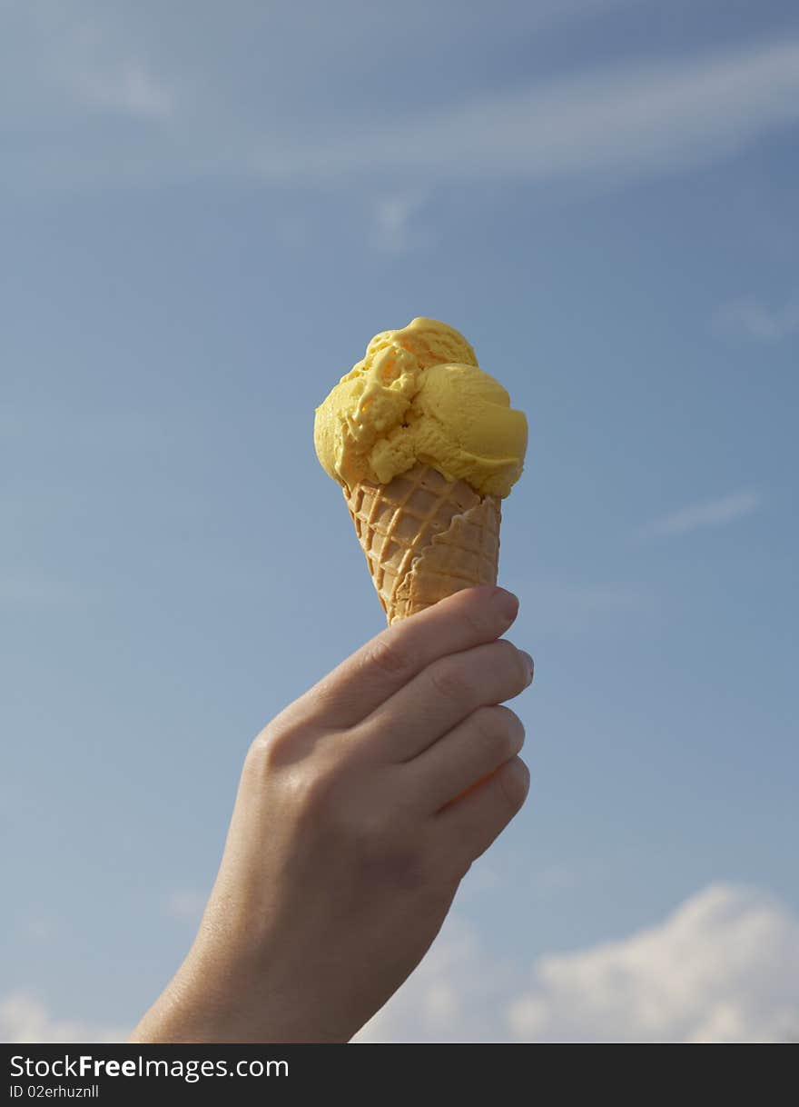 Ice cream in hand against the blue sky