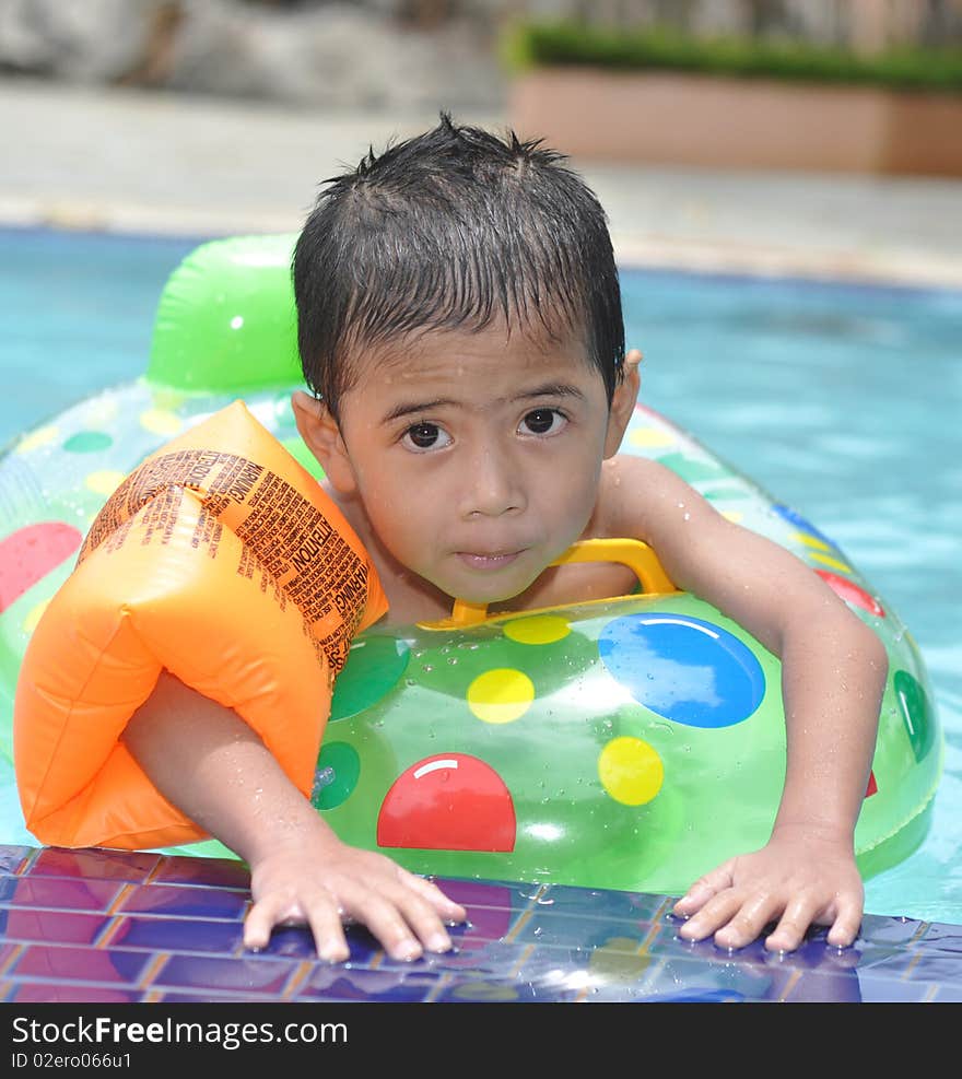 A happy young boy relaxing on the side of a swimming pool