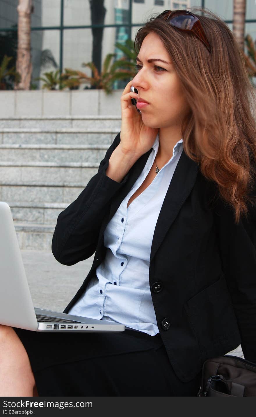 Business woman sitting on stairs with laptop and talking on the phone. Business woman sitting on stairs with laptop and talking on the phone