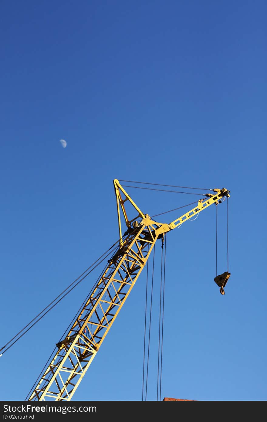 The yellow crane and moon in the blue sky vertical. The yellow crane and moon in the blue sky vertical