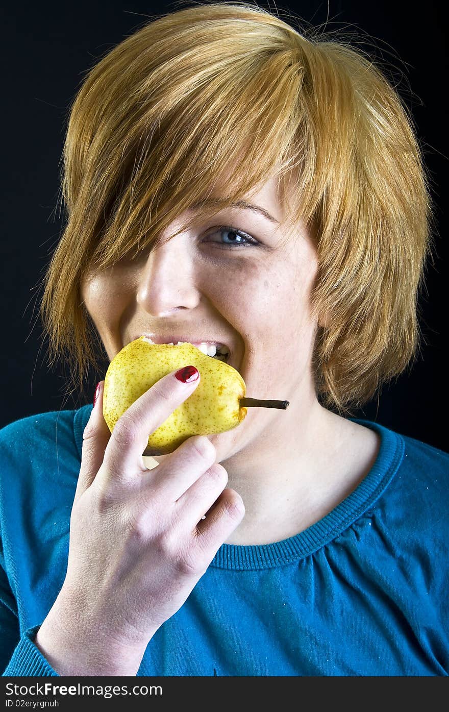 Cute blond girl eating a pear. Cute blond girl eating a pear