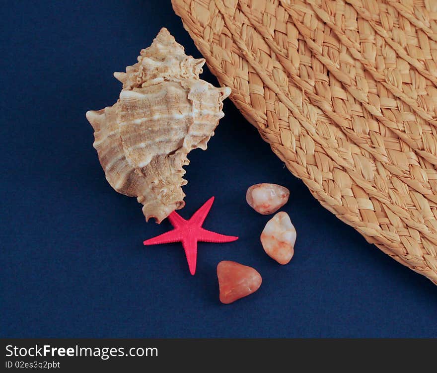 Shell, pebbles and sun hat on dark blue background. Shell, pebbles and sun hat on dark blue background