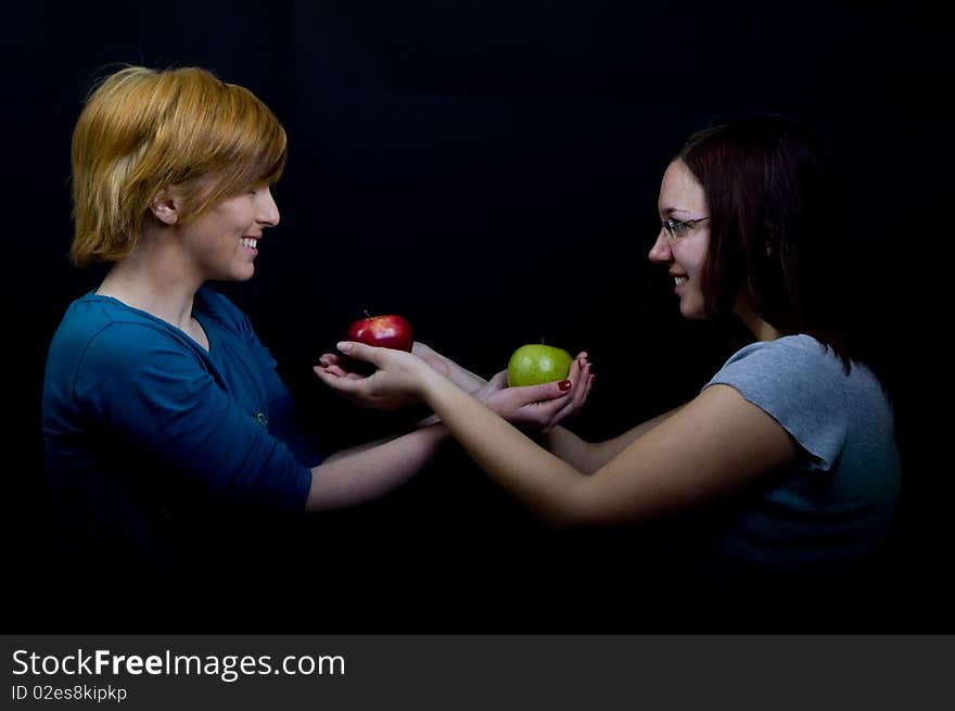 Two girls sharing colorful apples