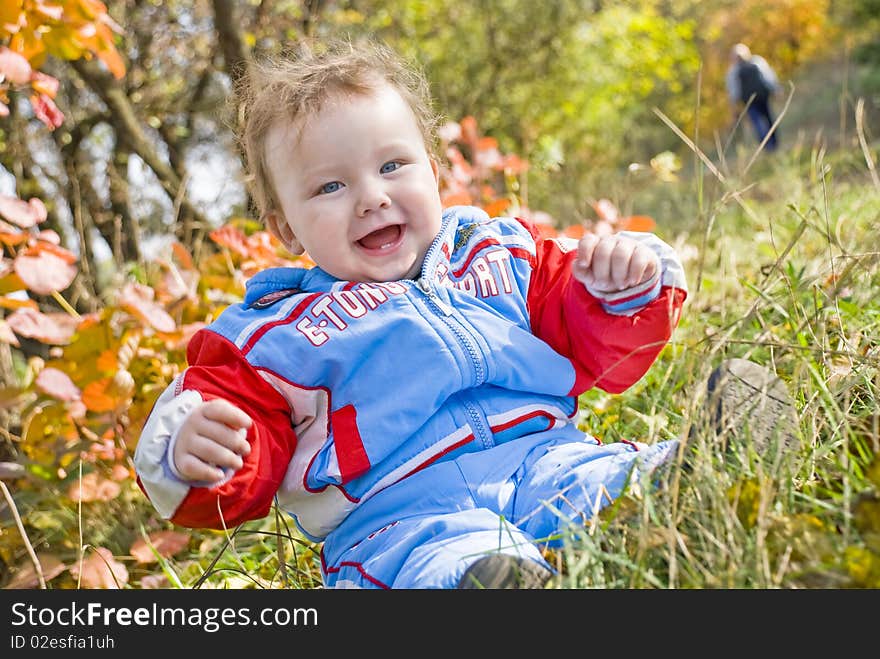 The boy sits on a meadow in park. The boy sits on a meadow in park