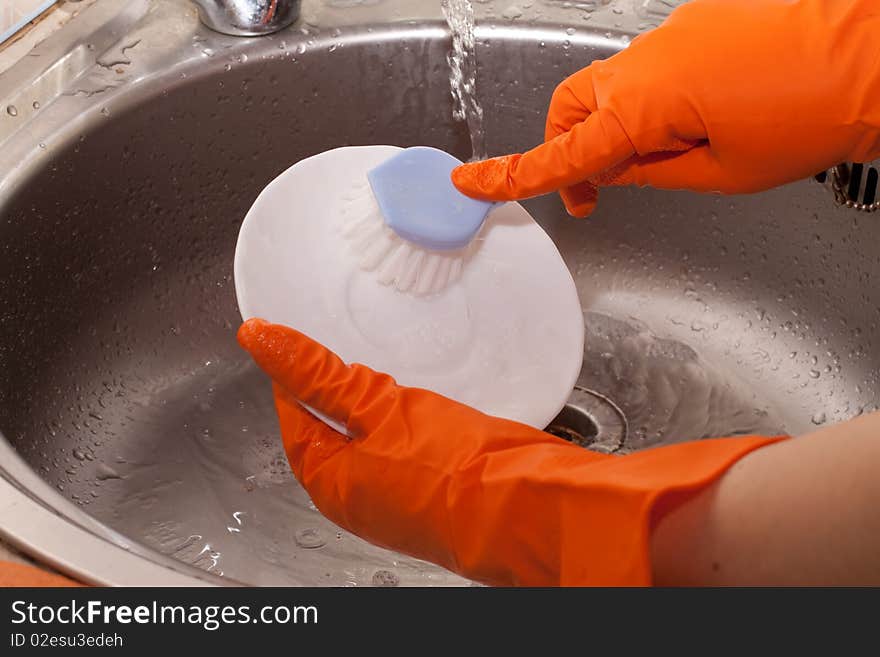 Women's hands in rubber gloves, wash the brush plate. Women's hands in rubber gloves, wash the brush plate