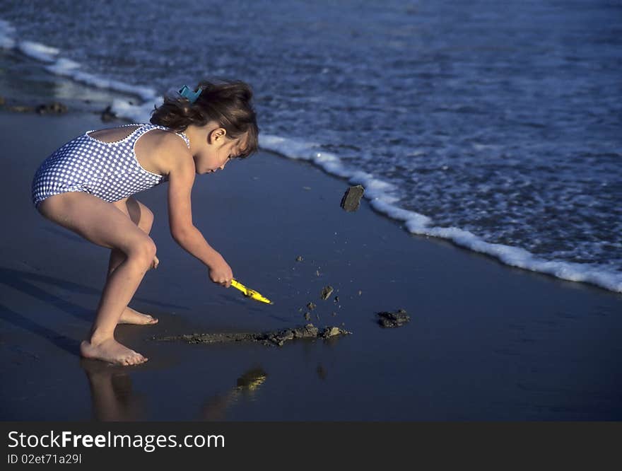 Little girl shoveling sand on