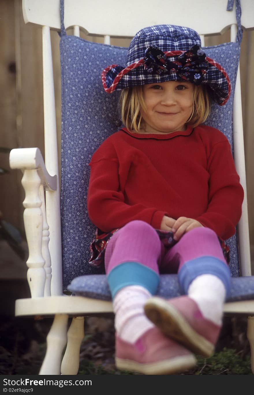 Toddler girl with a hat sitting in a chair. Toddler girl with a hat sitting in a chair