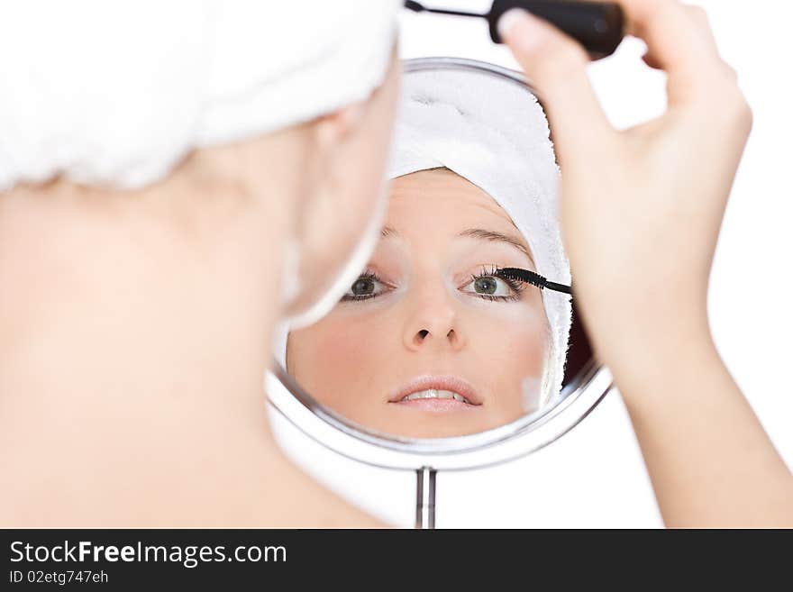 Woman painting eyelashes reflection in mirror with turban towel on head. Woman painting eyelashes reflection in mirror with turban towel on head