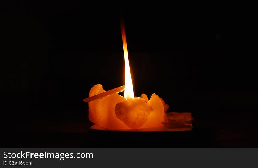 A sole lit candle to symbolise a light of hope in times of despair (darkness). A sole lit candle to symbolise a light of hope in times of despair (darkness)