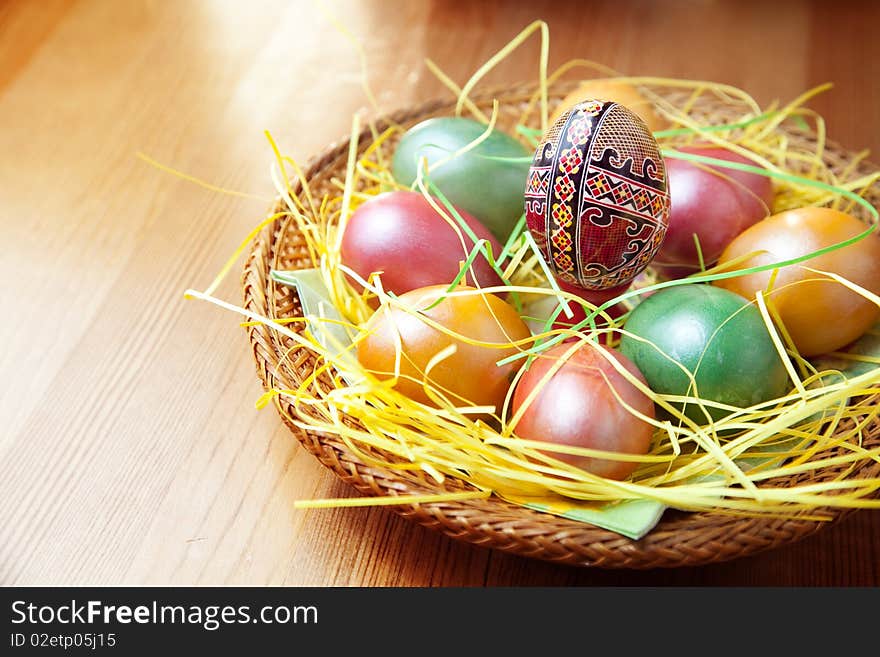 Easter painted eggs in traditional basket on table