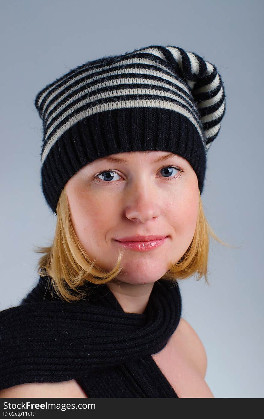 Portrait of a young pretty girl in black and white striped hat and scarf