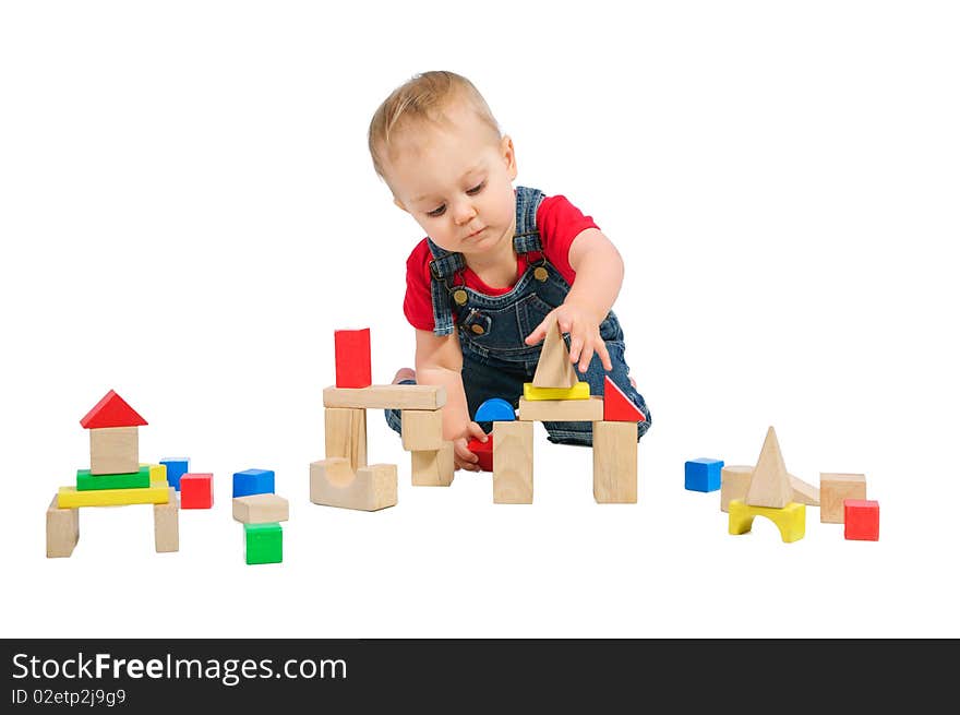 Little cute boy builds houses out of colored blocks. Little cute boy builds houses out of colored blocks