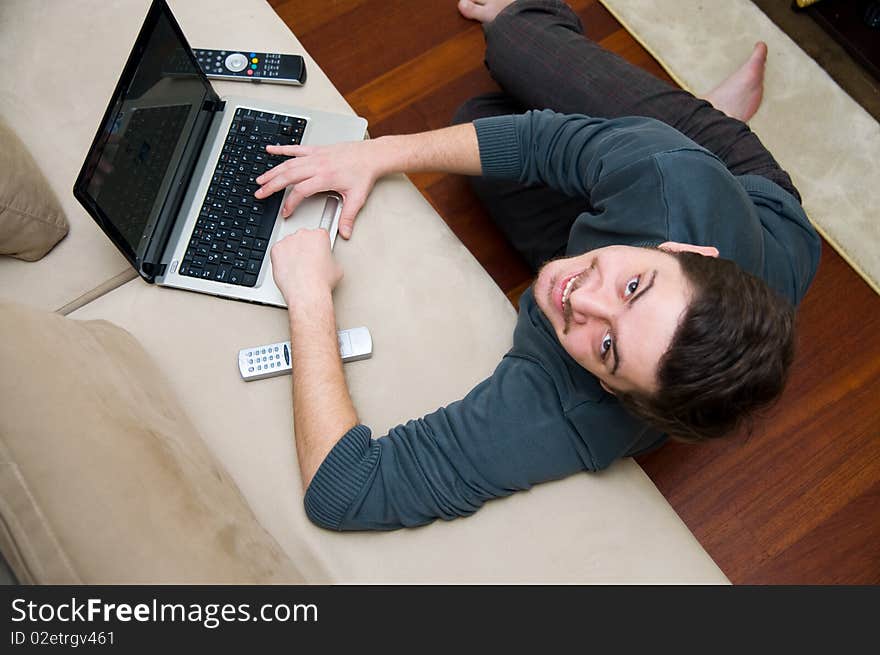 Portrait of a smiling man working on a laptop at home sitting on the couch. Portrait of a smiling man working on a laptop at home sitting on the couch