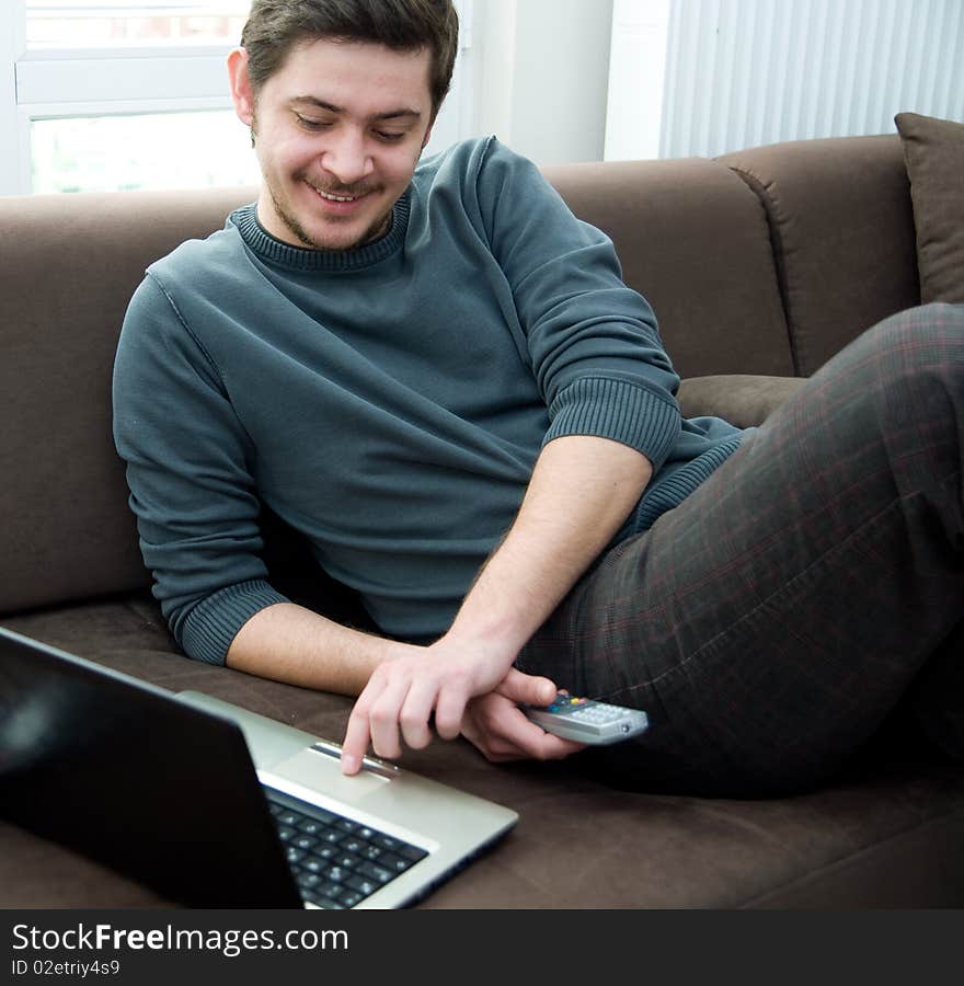 Portrait of a man working on a laptop at home sitting on the couch. Portrait of a man working on a laptop at home sitting on the couch