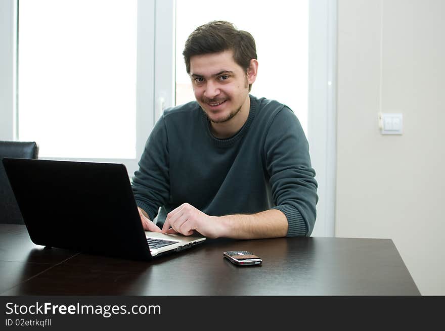 Portrait of a smiling man working on a laptop at home sitting on the couch. Portrait of a smiling man working on a laptop at home sitting on the couch