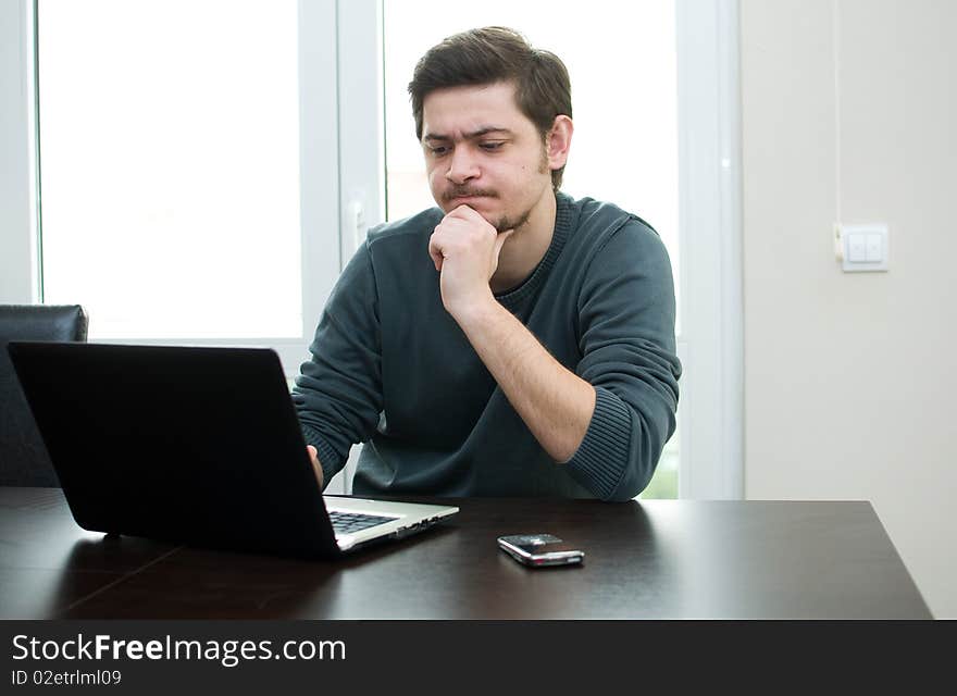 Portrait of a smiling man working on a laptop at home. Portrait of a smiling man working on a laptop at home