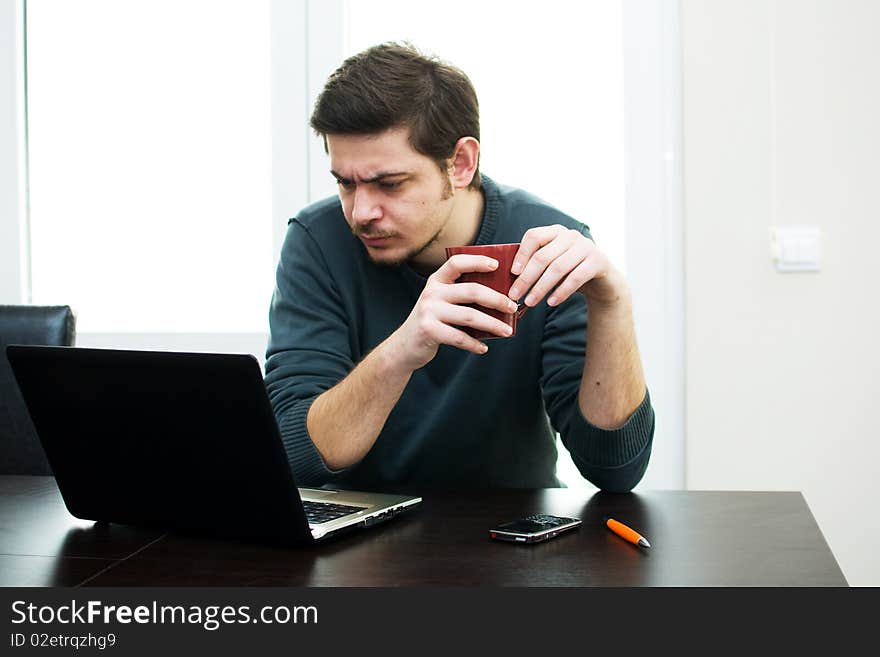 Portrait of a smiling man working on a laptop at home sitting on the couch. Portrait of a smiling man working on a laptop at home sitting on the couch