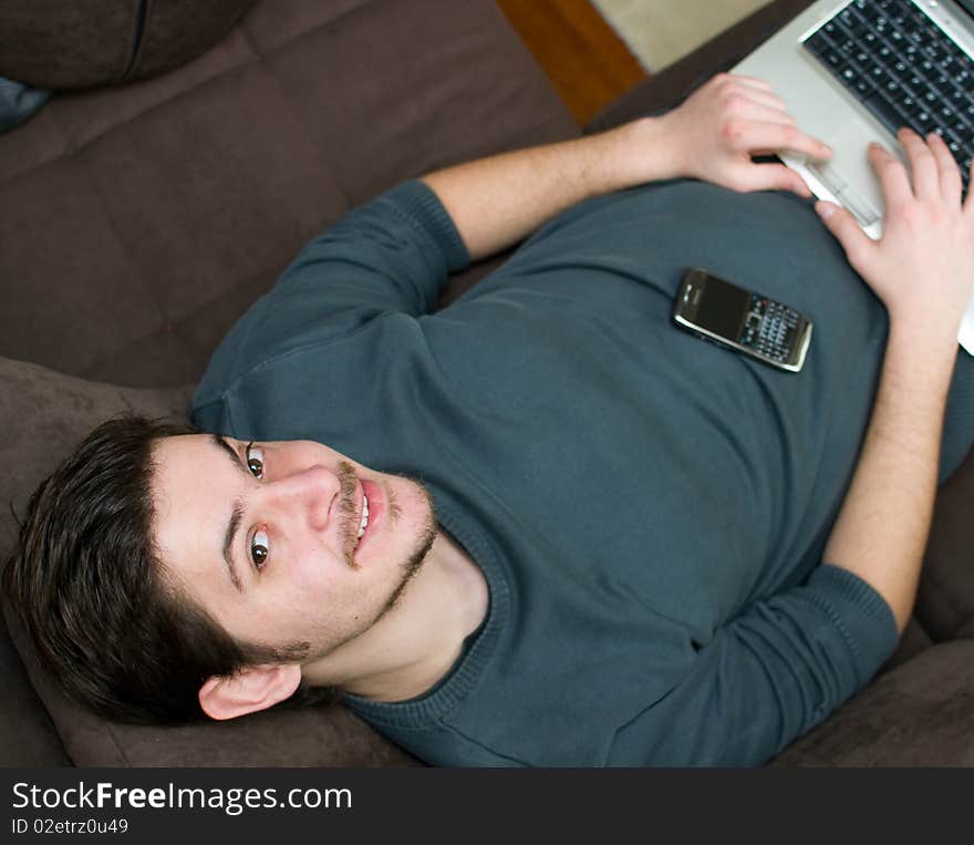 Portrait of a man working on a laptop at home lying on the couch. Portrait of a man working on a laptop at home lying on the couch