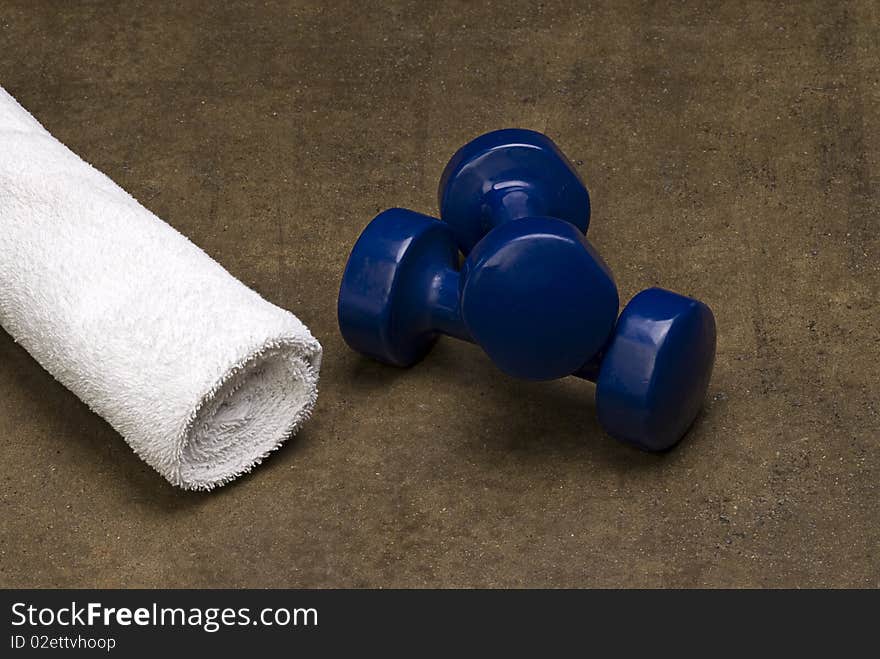 Blue dumbbells and a white towel isolated on a grungy textured background