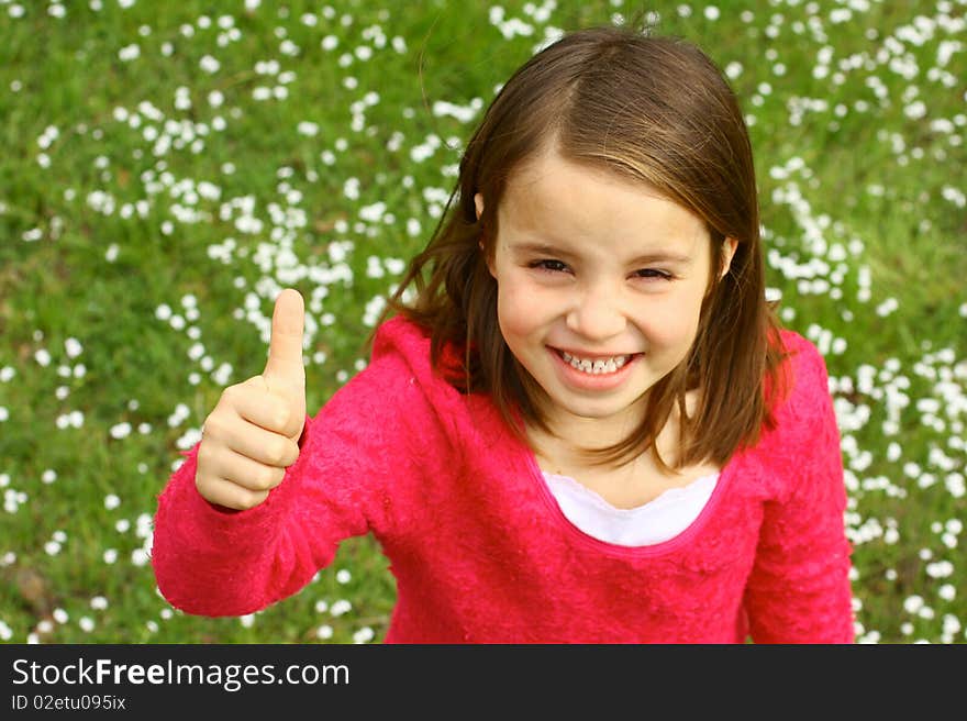 Cute little girl with thumb up and springtime grassy field. Cute little girl with thumb up and springtime grassy field.