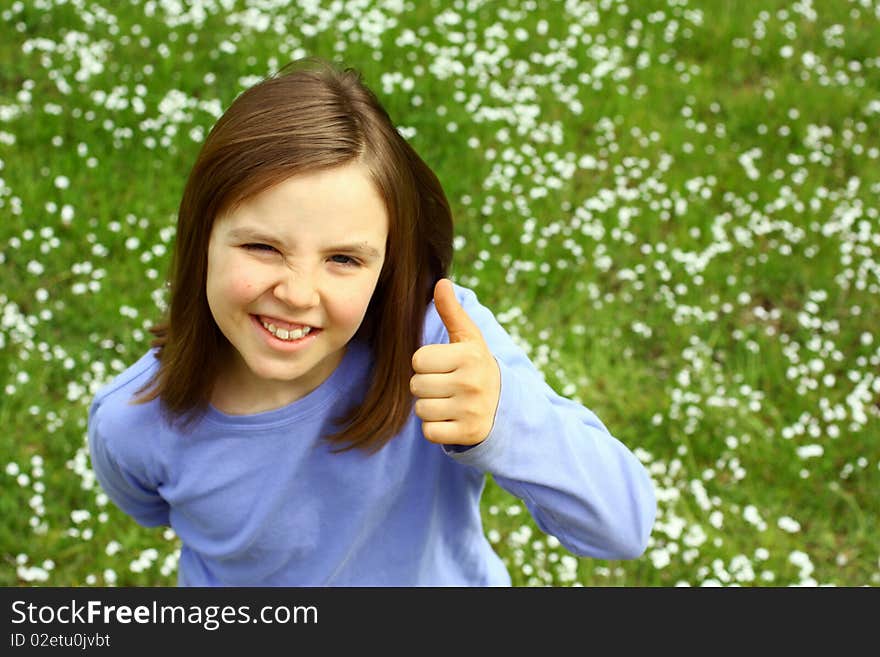 Cute little with thumb up and springtime grass in background. Cute little with thumb up and springtime grass in background.